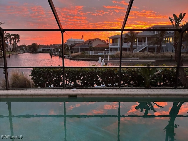 pool at dusk featuring a water view