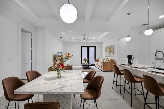 dining space featuring sink, a raised ceiling, and ceiling fan