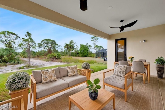 view of patio with ceiling fan, outdoor lounge area, and glass enclosure