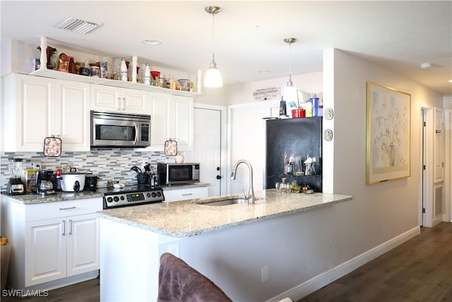 kitchen featuring white cabinetry, sink, light stone countertops, decorative light fixtures, and appliances with stainless steel finishes