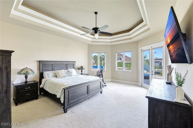 carpeted bedroom with access to exterior, french doors, ornamental molding, a tray ceiling, and ceiling fan