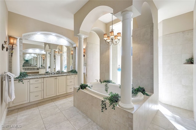 bathroom featuring decorative columns, vanity, an inviting chandelier, tile patterned flooring, and tiled bath