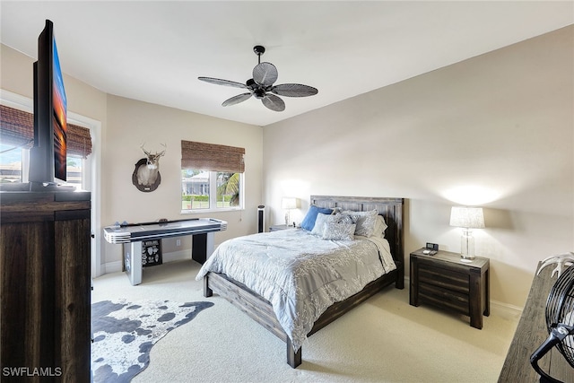 bedroom with ceiling fan, light colored carpet, and multiple windows