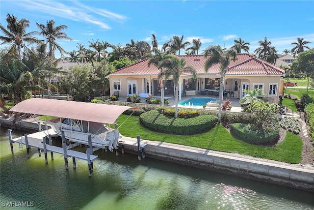 back of property with a water view, a patio area, and a lawn