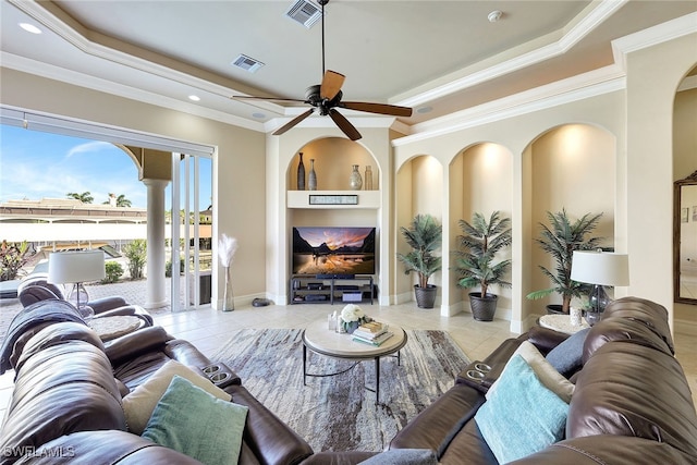 tiled living room with built in shelves, ceiling fan, and ornamental molding