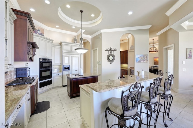 kitchen with a center island, backsplash, a kitchen breakfast bar, light tile patterned floors, and decorative light fixtures