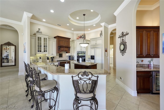 kitchen with decorative backsplash, a breakfast bar, a kitchen island, wine cooler, and hanging light fixtures