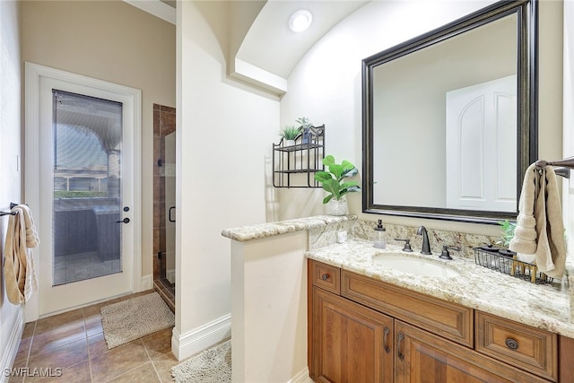 bathroom with a shower with door, vanity, and tile patterned flooring