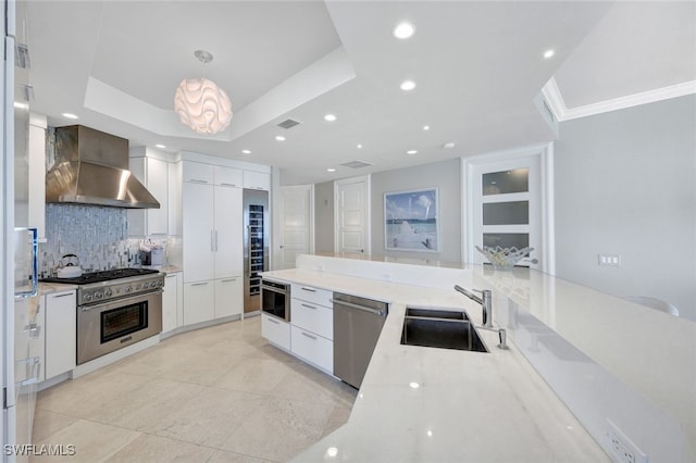 kitchen with pendant lighting, wall chimney range hood, sink, appliances with stainless steel finishes, and white cabinetry