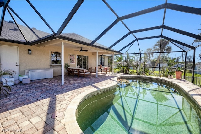 view of swimming pool with glass enclosure, ceiling fan, and a patio area