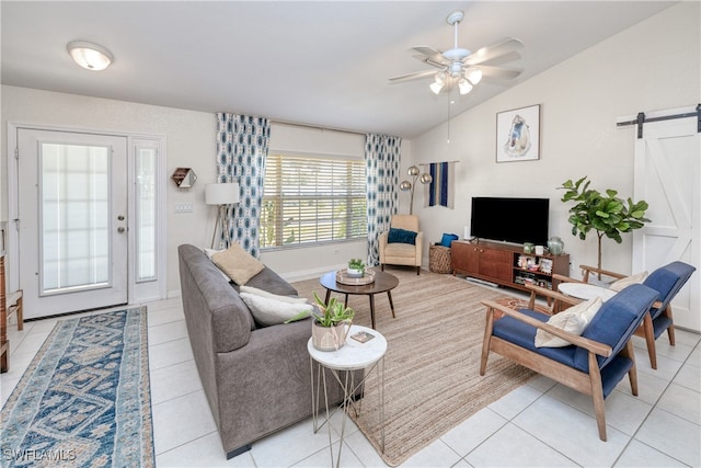 living room featuring a barn door, vaulted ceiling, ceiling fan, and light tile patterned flooring