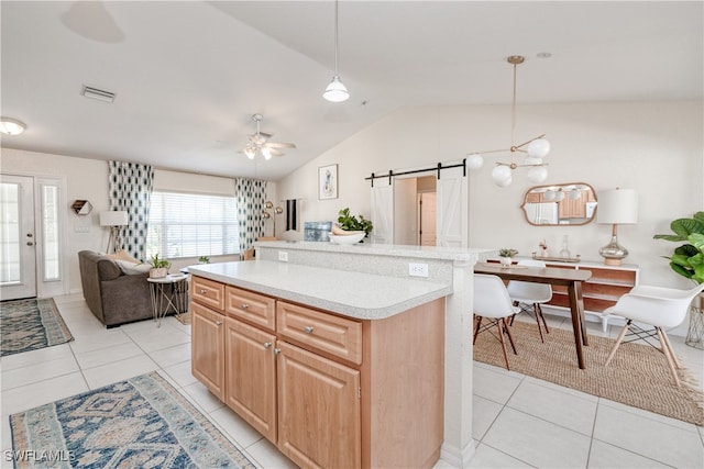 kitchen featuring a kitchen island, a barn door, lofted ceiling, decorative light fixtures, and light tile patterned floors