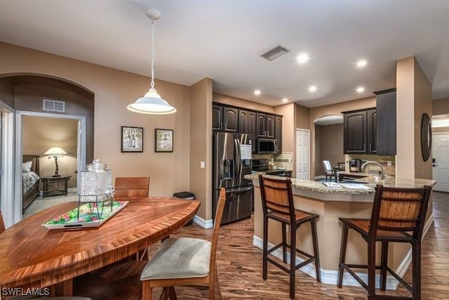 kitchen featuring appliances with stainless steel finishes, tasteful backsplash, light hardwood / wood-style flooring, and kitchen peninsula