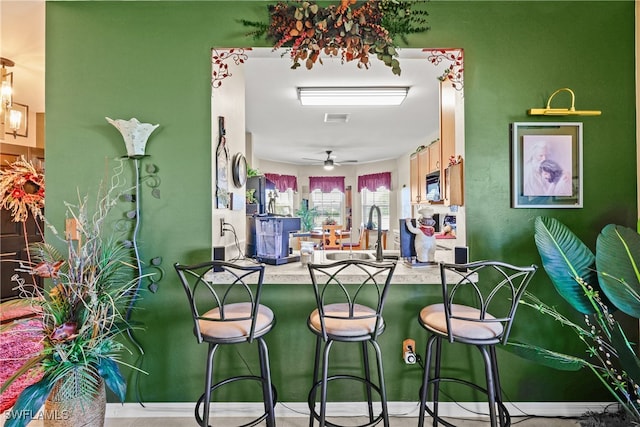 kitchen with a breakfast bar, ceiling fan, and sink