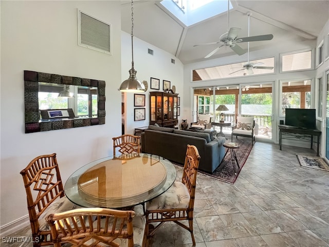 dining area with a skylight, ceiling fan, high vaulted ceiling, and a healthy amount of sunlight