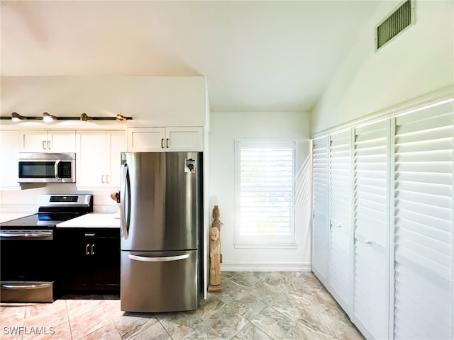 kitchen featuring white cabinetry, appliances with stainless steel finishes, and vaulted ceiling