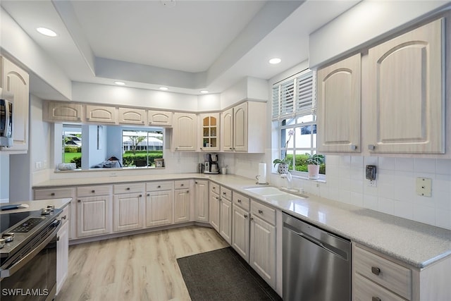 kitchen featuring decorative backsplash, light wood-type flooring, sink, and appliances with stainless steel finishes