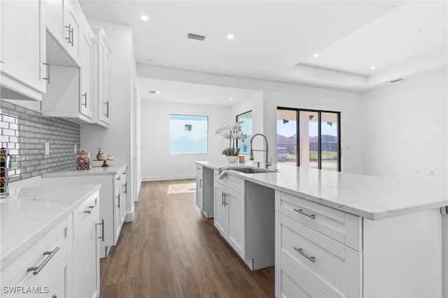 kitchen featuring decorative backsplash, dark hardwood / wood-style flooring, a kitchen island with sink, sink, and white cabinetry