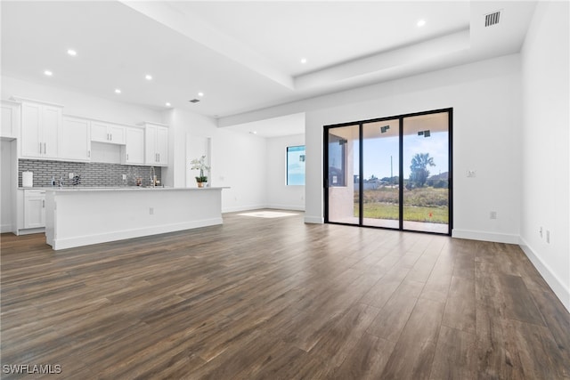 unfurnished living room with a raised ceiling and dark hardwood / wood-style flooring