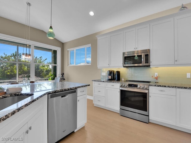 kitchen with stainless steel appliances, vaulted ceiling, light hardwood / wood-style flooring, white cabinetry, and hanging light fixtures