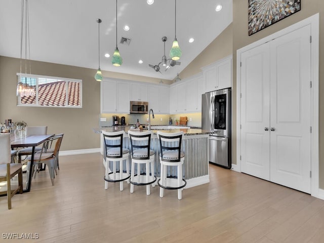 kitchen featuring a kitchen island with sink, white cabinetry, pendant lighting, and stainless steel appliances