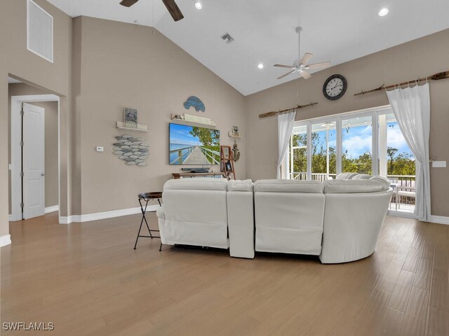 living room with ceiling fan, light hardwood / wood-style floors, and high vaulted ceiling