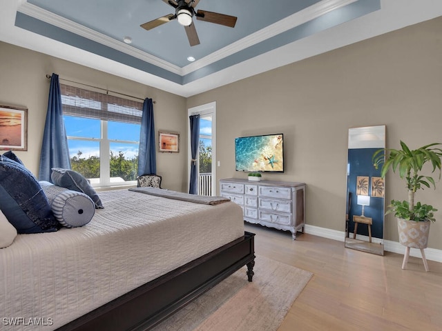 bedroom featuring ornamental molding, light hardwood / wood-style floors, ceiling fan, and a tray ceiling