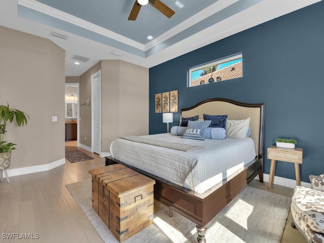 bedroom featuring ceiling fan, light hardwood / wood-style floors, a raised ceiling, and crown molding