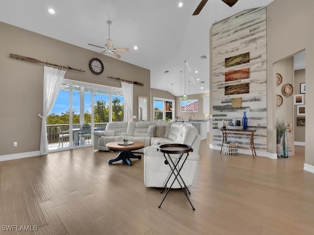 living room with light hardwood / wood-style floors, high vaulted ceiling, and ceiling fan