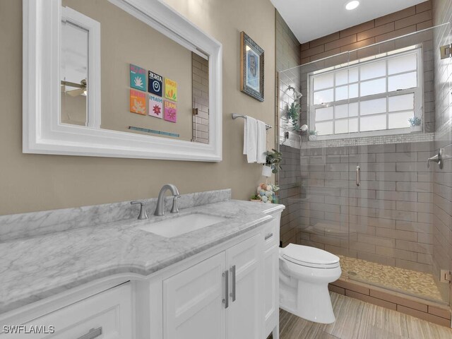 bathroom featuring tile patterned floors, vanity, a shower with shower door, and toilet