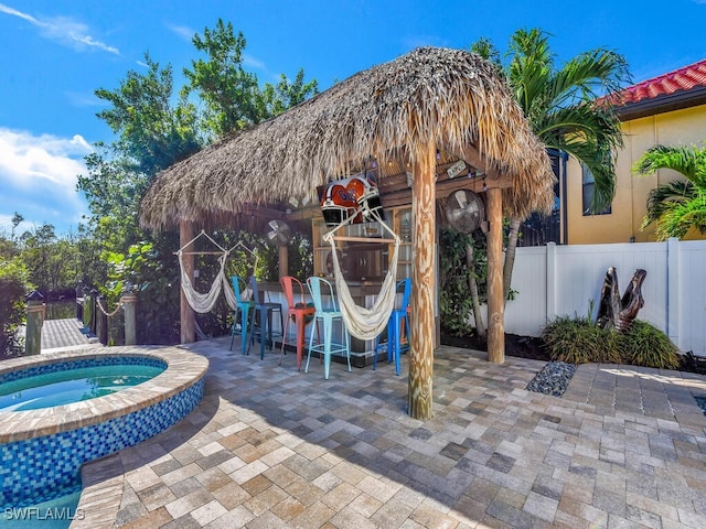 view of patio with a gazebo, an in ground hot tub, and exterior bar