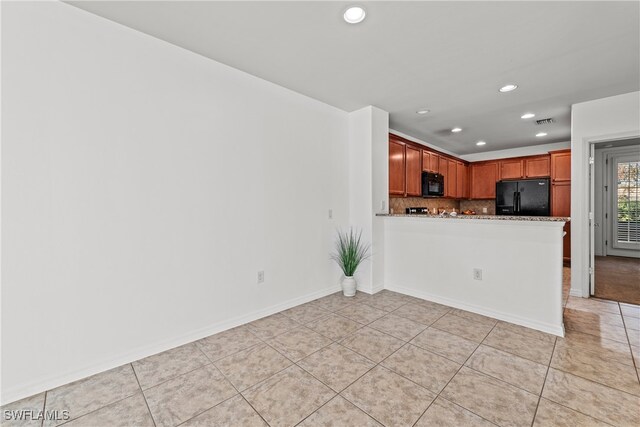 kitchen featuring black appliances, light tile patterned flooring, kitchen peninsula, and backsplash