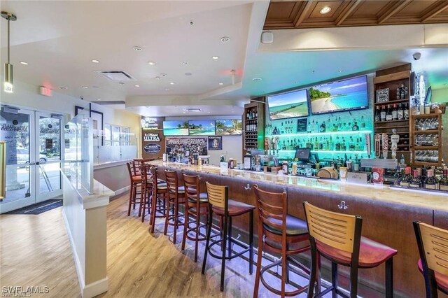 bar with light wood-type flooring and decorative light fixtures