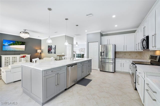 kitchen with pendant lighting, white cabinets, stainless steel appliances, tasteful backsplash, and a center island with sink