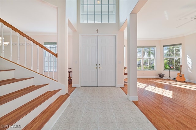 foyer featuring stairs, wood finished floors, baseboards, and ornamental molding