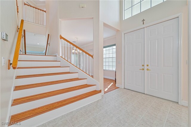 foyer entrance featuring baseboards, a towering ceiling, and stairs