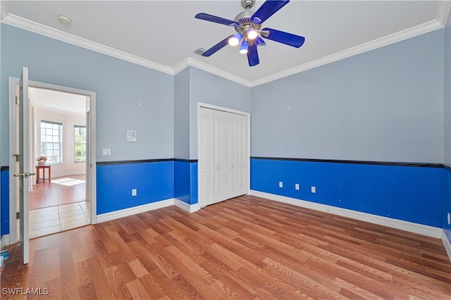 empty room featuring baseboards, crown molding, a ceiling fan, and wood finished floors