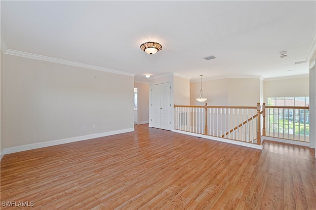 unfurnished room with ornamental molding, light wood-style floors, visible vents, and baseboards