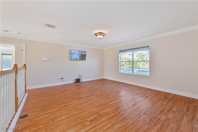 empty room with visible vents, light wood-type flooring, baseboards, and ornamental molding