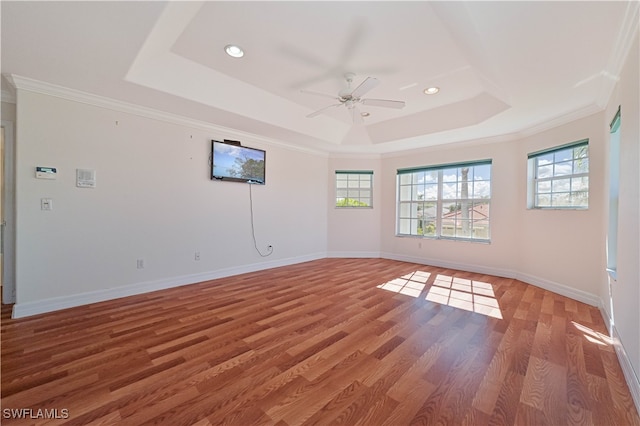 unfurnished room featuring a tray ceiling, baseboards, light wood finished floors, and ornamental molding