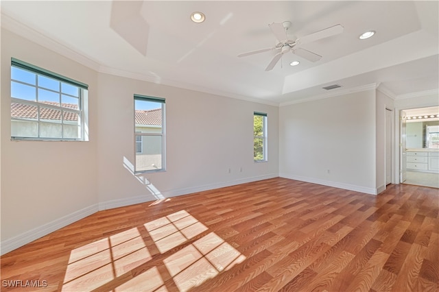 unfurnished room with light wood-type flooring, visible vents, a raised ceiling, and baseboards