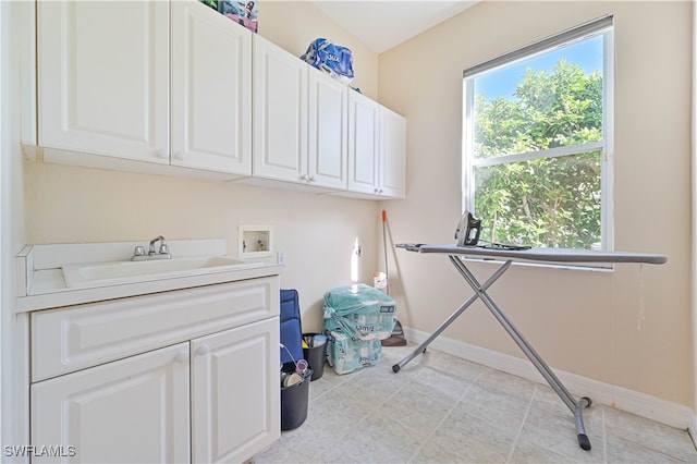 clothes washing area featuring a sink, baseboards, cabinet space, and washer hookup