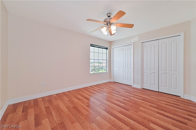 unfurnished bedroom featuring light wood-type flooring, baseboards, and two closets