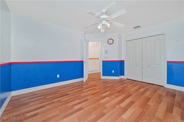 unfurnished bedroom featuring visible vents, wood finished floors, a closet, baseboards, and ceiling fan