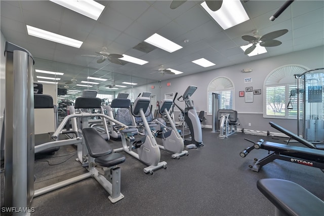 workout area featuring a ceiling fan, a paneled ceiling, and baseboards