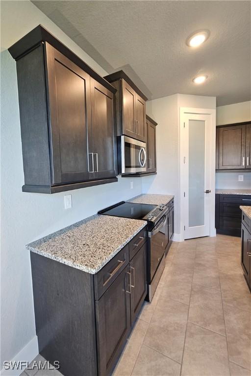 kitchen featuring light stone countertops, appliances with stainless steel finishes, and dark brown cabinetry