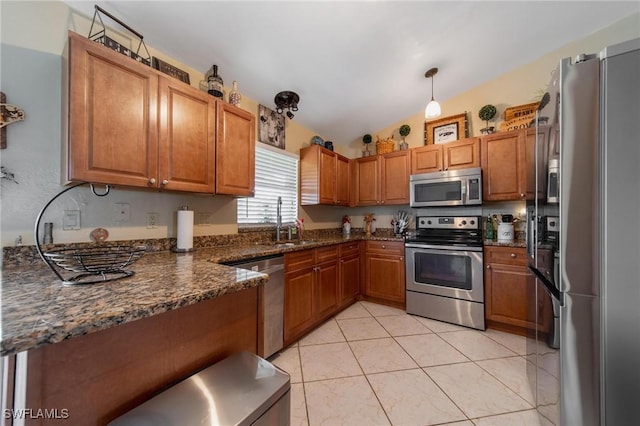 kitchen with sink, hanging light fixtures, stainless steel appliances, dark stone countertops, and lofted ceiling