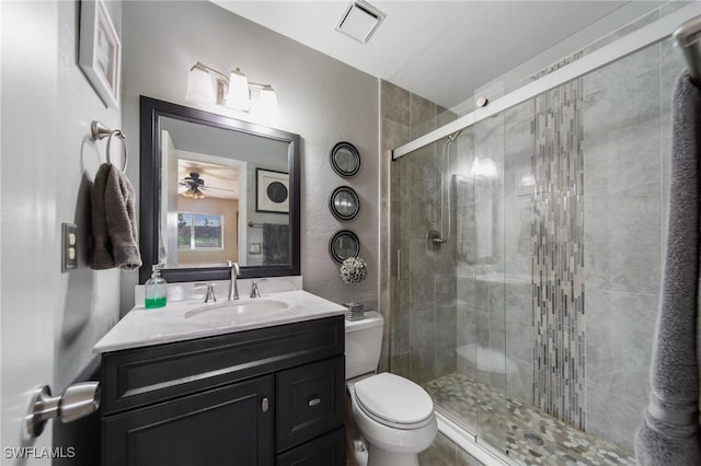 bathroom featuring vanity, toilet, walk in shower, and ceiling fan