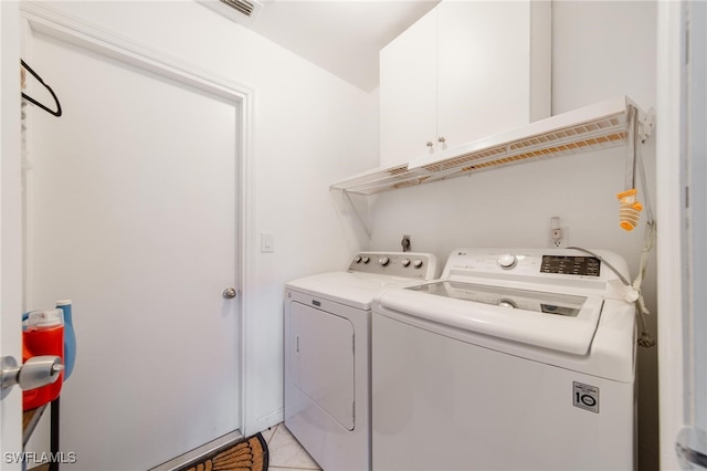 washroom featuring cabinets, light tile patterned floors, and washing machine and dryer