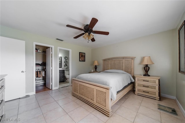 bedroom featuring ensuite bathroom, a walk in closet, ceiling fan, light tile patterned flooring, and a closet